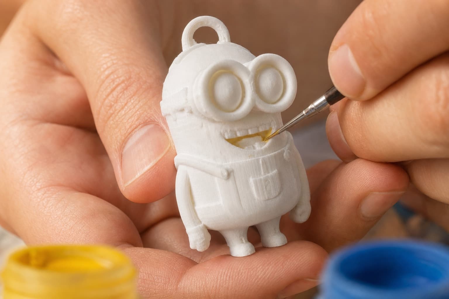 Unas manos pintando un Minion impreso en 3D en la sede de AKUMAYA